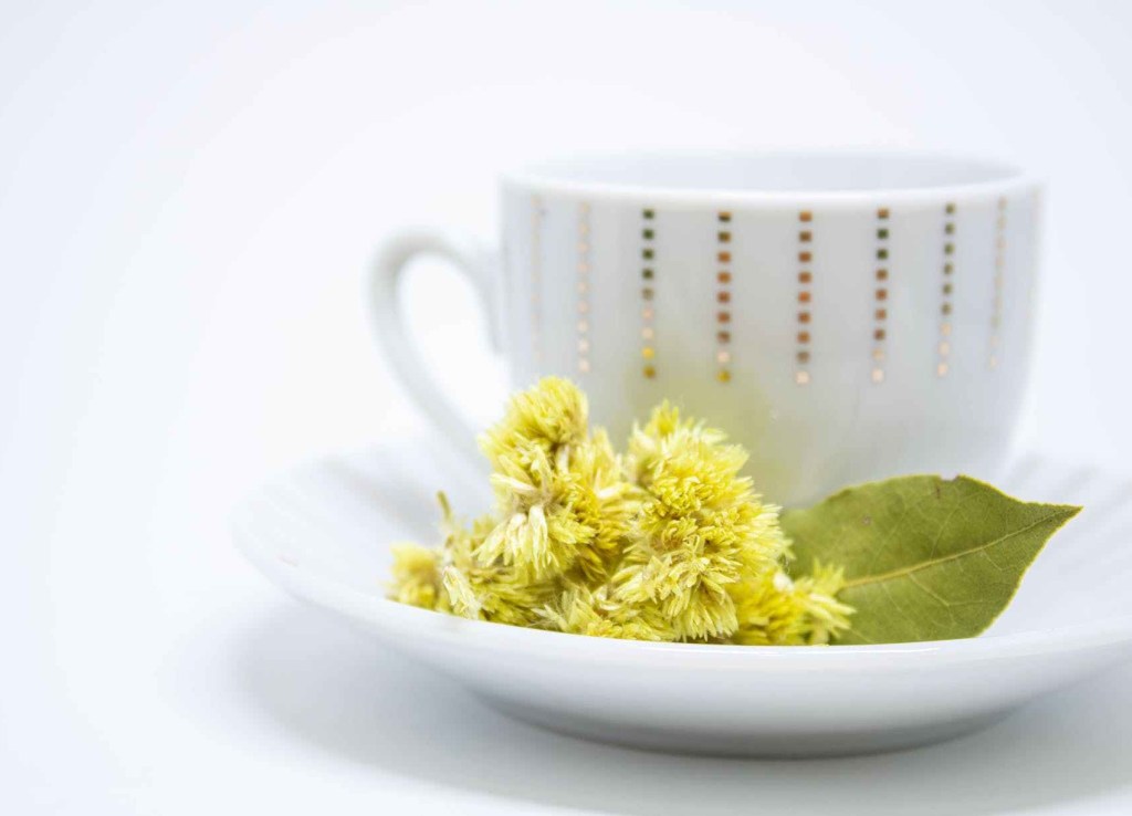 Picture of a white mug with yellow flowers and a leaf on the side of the saucer.